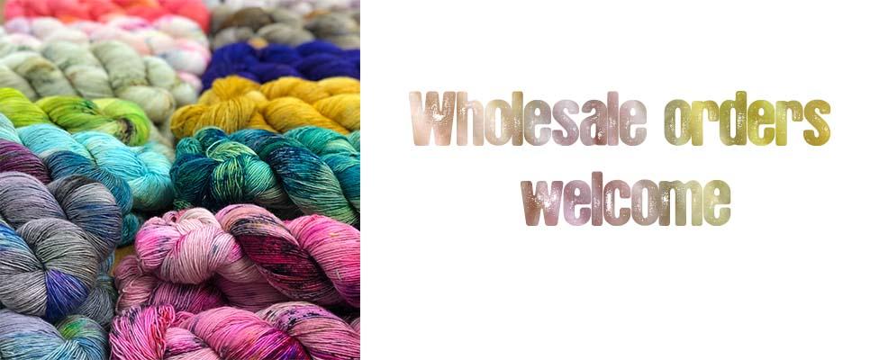 Photo of table covered in skeins of yarn with text wholesale orders welcome